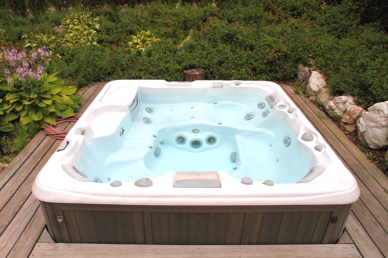 A new hot tub sits down in a beautiful deck with lovely shrubs surrounding. Get a loan for a new hot tub through HFS Financial.