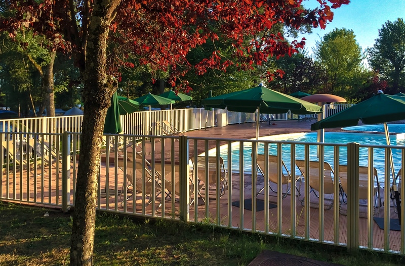 A child safety fence surrounds a lovely in-ground swimming pool.