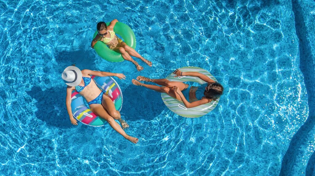 Three women in doughnut floats enjoying the pool.