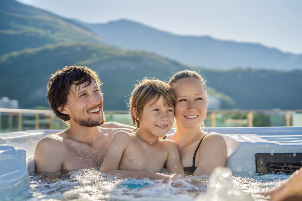 A family of three sitting in a hot tub financed by HFS Financial in the mountains