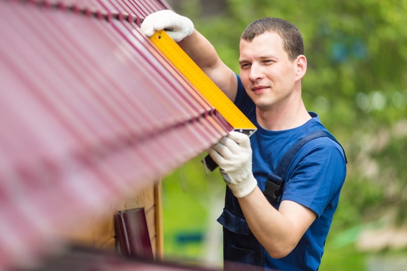 professional roofer measures roofing material for installation
