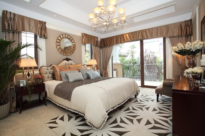 a master bedroom with a big bed and rug and light fixture