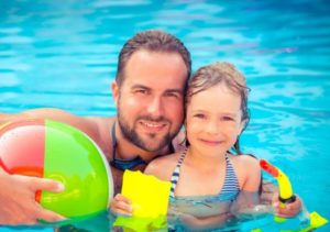 Father and daughter smiling in pool