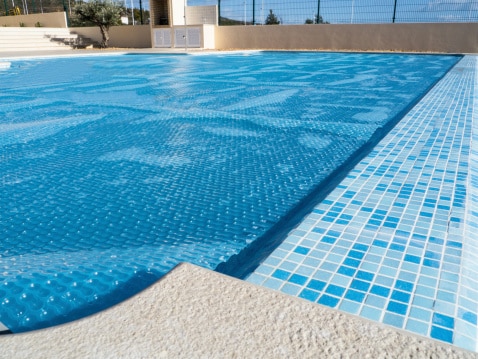 Pool cover in good condition deployed over outdoor pool
