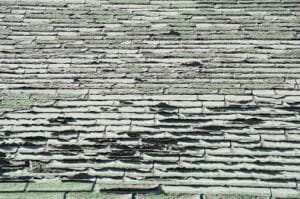a shabby roof with curling, cracked shingles that need to be replaced