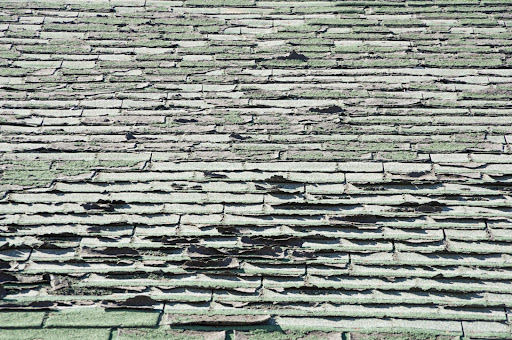 a shabby roof with curling, cracked shingles that need to be replaced