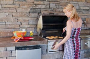 woman cooking and grilling in an outdoor kitchen with concrete countertop