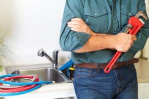Professional holding a monkey wrench fixing a sink in a kitchen remodel with financing for contractors