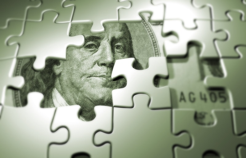 The image of Benjamin Franklin on a $100 bill peeks from behind some missing puzzle pieces to signify that home remodels are expensive and often require contractor financing.