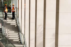two construction workers talking at the top of a staircase