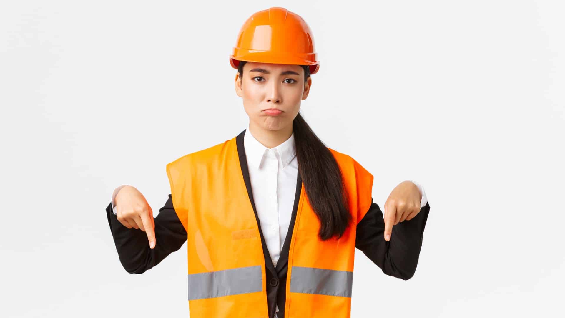 This frowning construction worker with her thumbs pointing down is wondering how to break bad news to her construction clients.