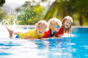 Children in pool swimming with paddleboard