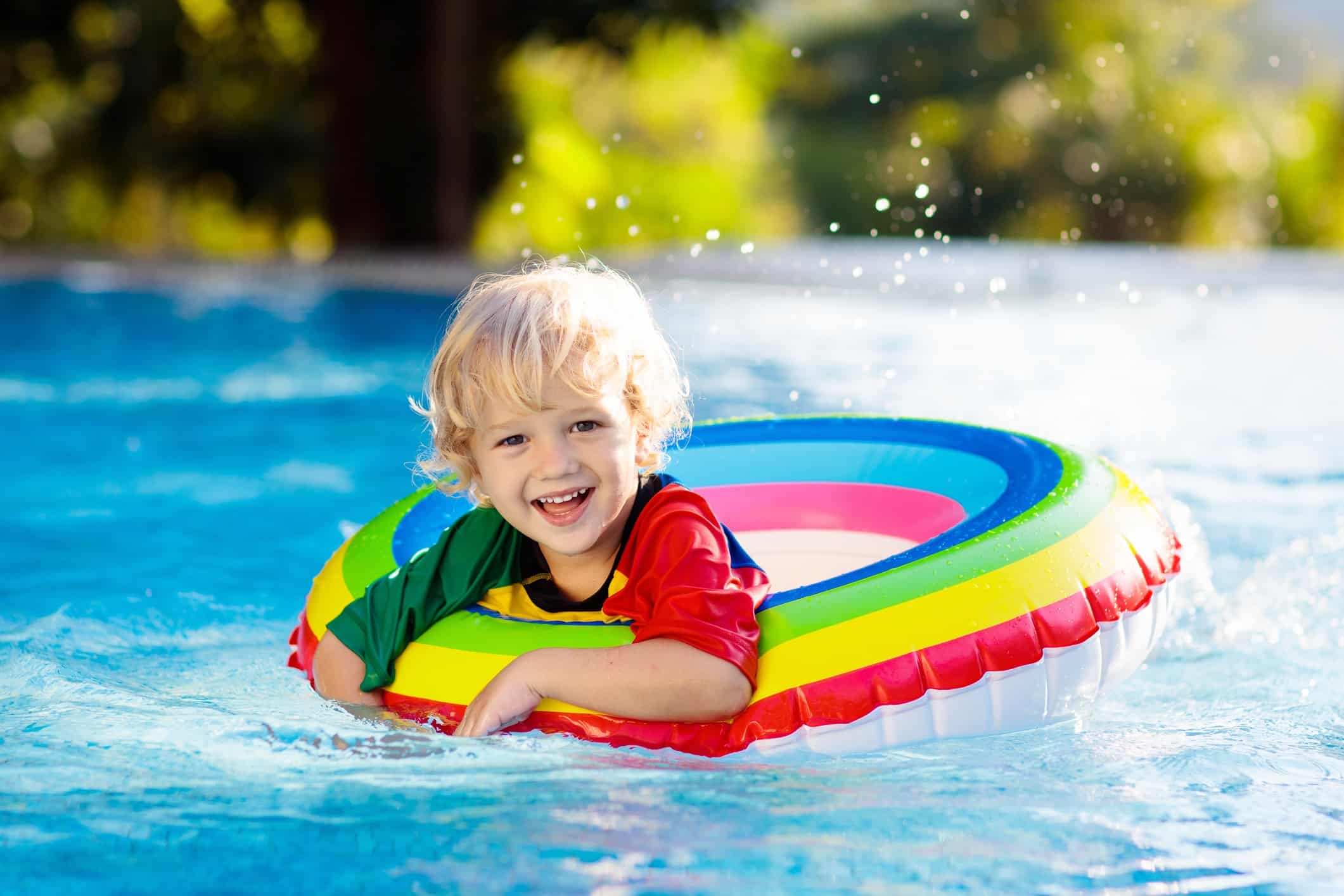 Boy in inner tube splashing in pool