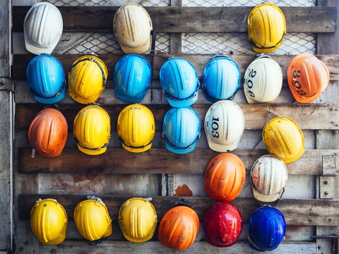 Multi-colored hard hats hang on wooden slats as contractors prepare for the off-season.