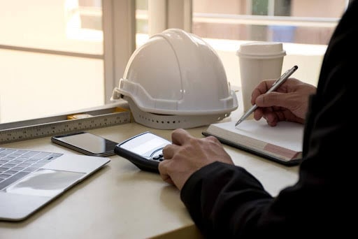 A general contractor at his desk solving cash flow issues with a calculator and general contractor financing