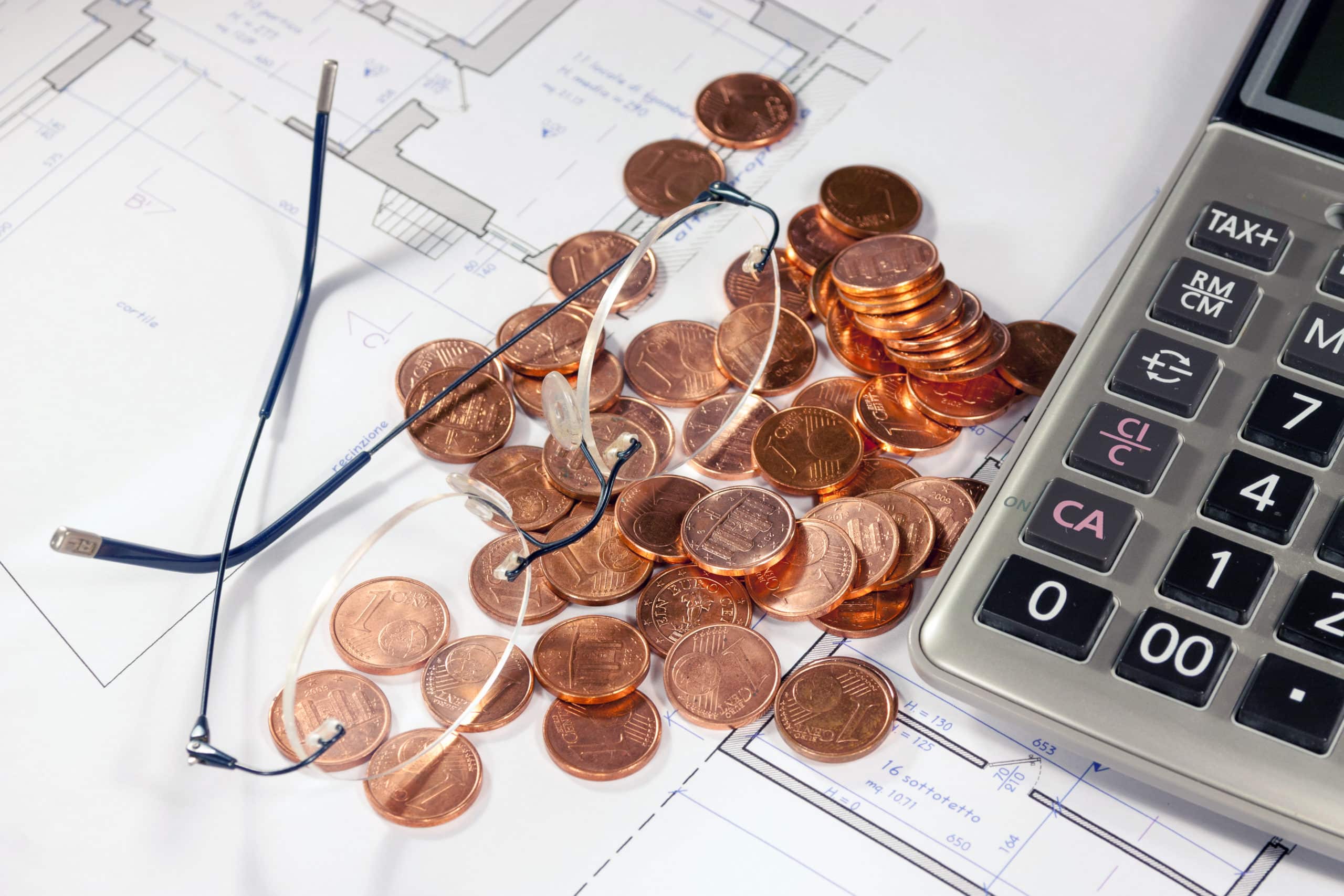 a calculator sits next to a pile of coins and a pair of glasses as a contractor considers how offering contractor financing can increase cashflow in the off-season