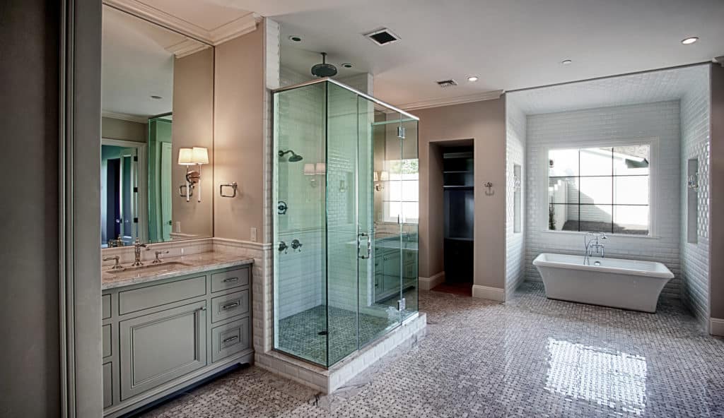 A kitchen and bath remodeling business has completed a beautiful bath remodel with a glass shower and tile. 