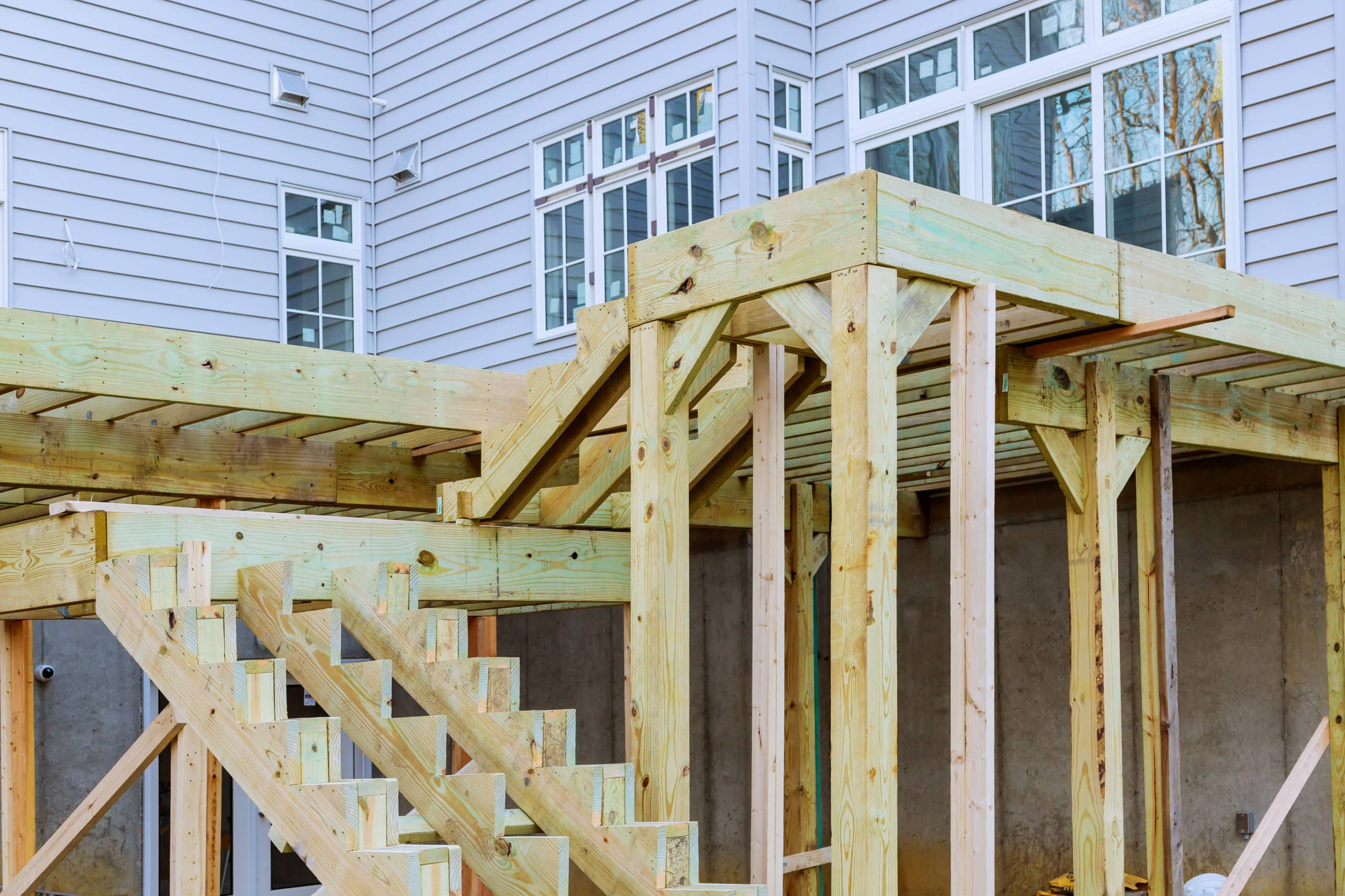The raw wood of a partially finished double level deck showcases the work of a local deck and patio business.
