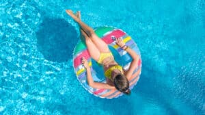 A woman floats in a pink and yellow inner tube in her pool that she got with a swimming pool loan from HFS Financial.
