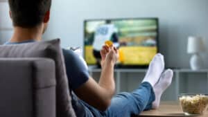 Man eats chips and watches TV in his man cave that he added to his home with man cave loans